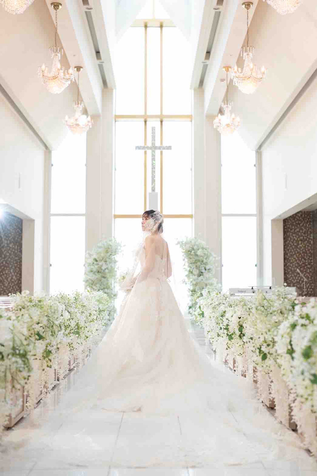 白いチャペルの中でたたずむウエディングドレスを着た新婦